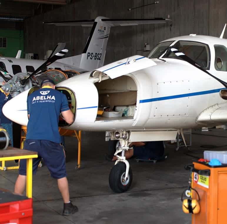 Mecânicos da Abelha trabalhando em um Cheyenne prefixo PS-BSZ com o compartimento de nariz aberto, dentro do hangar