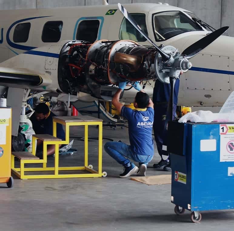 Mecânicos de uniforme da Abelha trabalhando na turbina exposta de um Cheyenne